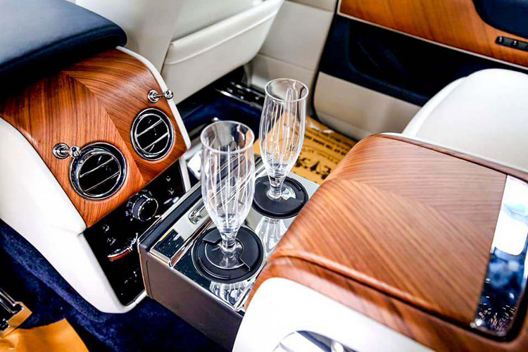 Khoang nội thất xe sử dụng tông màu trắng nổi bật nhưng không kém phần sang trọng, đi kèm ốp gỗ Veneer tối màu được điểm xuyết bằng đường viền đẹp mắt – tùy chọn ít thấy trên những chiếc Cullinan tại Việt Nam. Hàng ghế trước chỉnh điện đa hướng cùng bệ tỳ tay sưởi ấm.