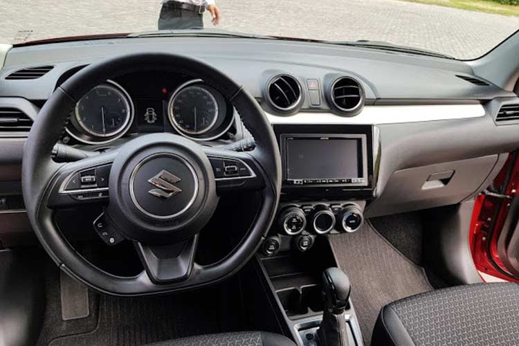 Đáng tiếc là Suzuki Swift mới lại trung thành với thiết kế “truyền thống” ốp nhựa cho táp-lô, viền cửa và bọc nỉ ghế ngồi. Vô-lăng trên phiên bản GL của Suzuki Swift 2018 được bọc Urethane, tích hợp nút chỉnh âm thanh trong khi đó bản GLX sẽ được bọc da, tích hợp nút điều khiển hành trình và thoại rảnh tay.