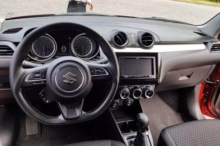 Đáng tiếc là Suzuki Swift mới lại trung thành với thiết kế “truyền thống” ốp nhựa cho táp-lô, viền cửa và bọc nỉ ghế ngồi. Vô-lăng trên phiên bản GL của Suzuki Swift 2018 được bọc Urethane, tích hợp nút chỉnh âm thanh trong khi đó bản GLX sẽ được bọc da, tích hợp nút điều khiển hành trình và thoại rảnh tay.