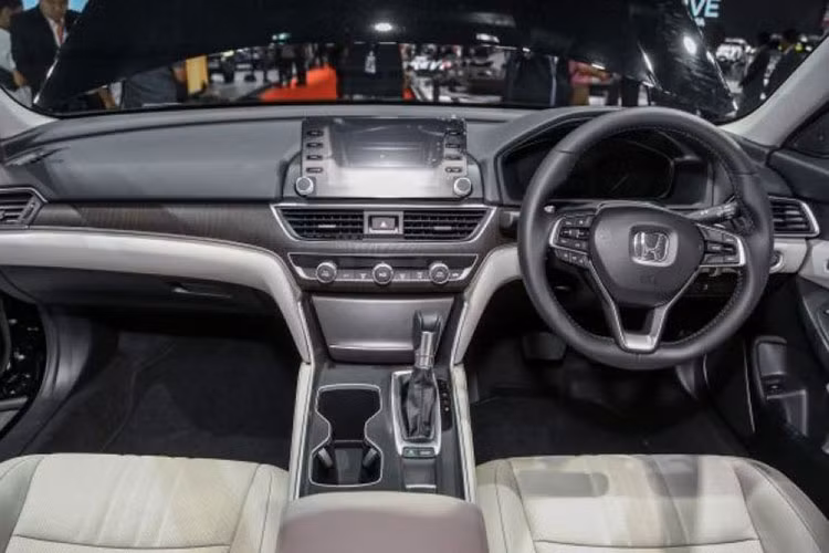Khoang nội thất của Honda Accord 2019 cũng sở hữu ngôn ngữ thiết kế mới, đơn giản và sang trọng. Bảng đồng hồ kỹ thuật số, màn hình thông tin giải trí nằm độc lập trên mặt táp-lô và 2 hộc để cốc nằm song song với cụm điều khiển trung tâm. Bên dưới màn hình giải trí trung tâm là cửa gió điều hòa và các núm chỉnh cơ tiện dụng.