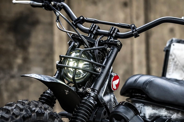 Có thể thấy, bản độ CT125 Combat đã mang lại vẻ ngoài hoàn toàn mới mẻ so với chiếc Honda CT125 nguyên bản. Ở dàn đầu xe thì đèn pha đã được thay thế bằng một đèn độ nhỏ gọn hơn, đi kèm với đó là lưới bảo vệ bằng kim loại dày dặn ở phía trước.