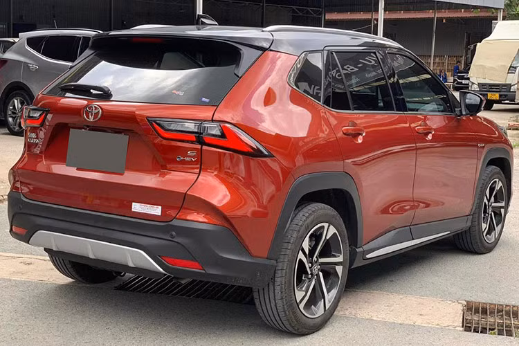 Cụm đèn hậu của Toyota Yaris Cross HEV 2023 cũng có thiết kế góc cạnh và được kéo dài sang hai bên. Xe sử dụng vành la-zăng 18 inch với hai màu sơn tương phản, đi kèm hốc bánh xe ốp nhựa hầm hố.