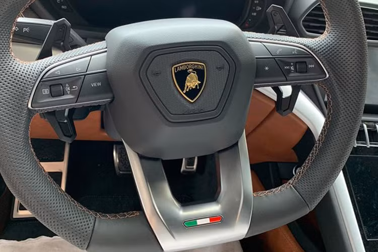 Đối lập với bộ áo ghi xám, chiếc Lamborghini Urus thứ 2 tại thị trường Việt Nam sở hữu nội thất màu da bò đi kèm các điểm nhấn như chỉ khâu tương phản với màu da, một số chi tiết bằng sợi carbon hay kim loại bóng.
