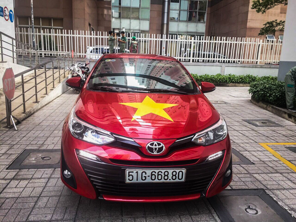 Tại một showroom của Toyota thuộc quận 1 (TP.HCM), mẫu Toyota Vios 2018 bản trưng bày cũng in hình biểu tượng quốc kỳ. Nhân viên tại showroom này cũng diện trang phục áo đỏ in hình sao vàng để truyền lửa cho các cầu thủ thi đấu thành công tại ASIAD.