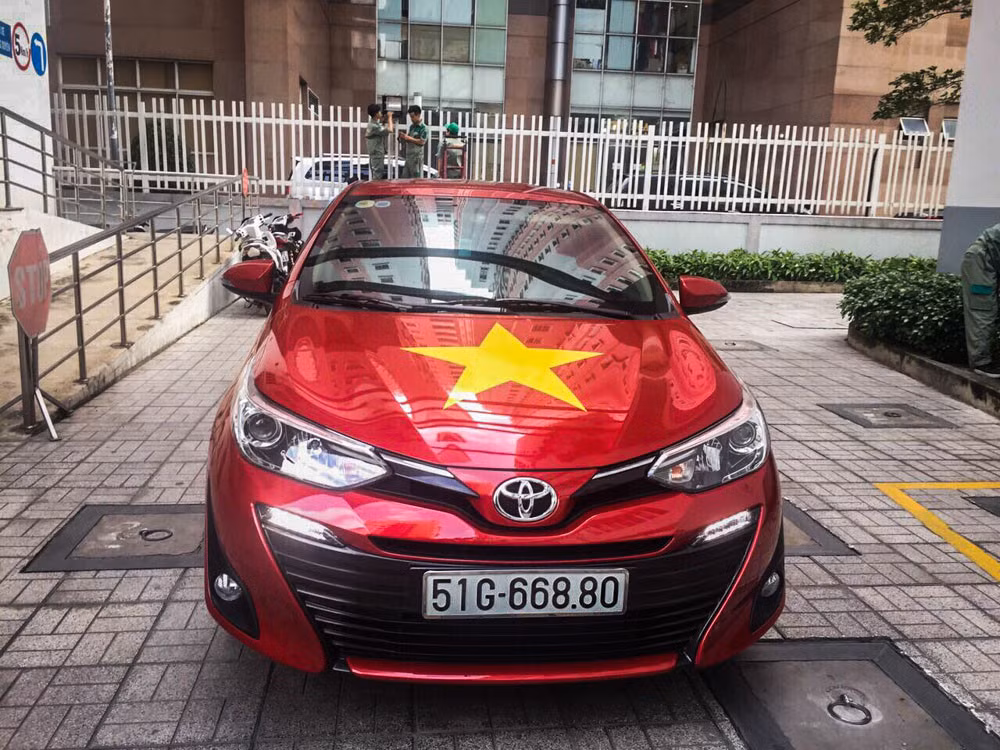 Tại một showroom của Toyota thuộc quận 1 (TP.HCM), mẫu Toyota Vios 2018 bản trưng bày cũng in hình biểu tượng quốc kỳ. Nhân viên tại showroom này cũng diện trang phục áo đỏ in hình sao vàng để truyền lửa cho các cầu thủ thi đấu thành công tại ASIAD.