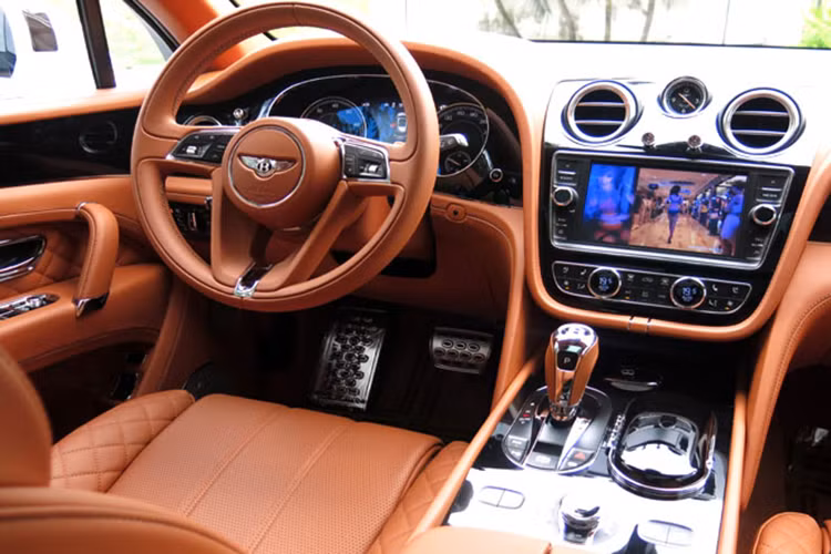 Bên trong mẫu siêu SUV này, toàn bộ da bọc nội thất của xe là da thật. Vô-lăng bọc da chỉnh điện mềm mại, nhiều nút bấm chức năng và tích hợp lẫy chuyển số. Cửa gió điều hoà mạ crôm đặc trưng Bentley. Bảng đồng hồ cơ cổ điển phong cách thể thao. Bảng điều khiển trung tâm trang bị màn hình cảm ứng 8 inch tiêu chuẩn.