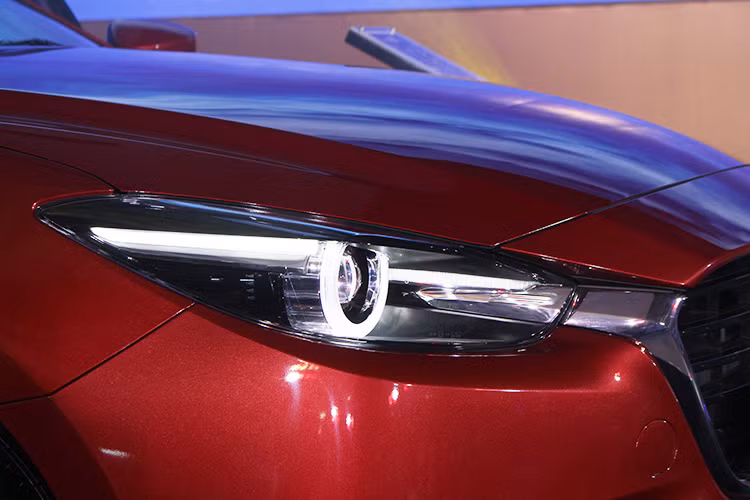 Điểm thu hút đầu tiên về ngoại thất của Mazda3 mới chính là hệ thống đèn chiếu sáng. Cụm đèn pha không chỉ được thiết kế lại sắc sảo hơn mà còn tích hợp công nghệ LED thích ứng thông minh AFS. Hệ thống ánh sáng AFS có thể mở góc chiếu sáng khi đánh lái.