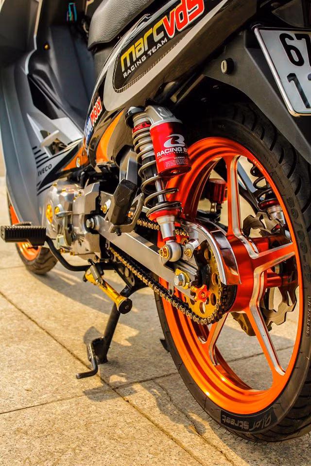 Phuộc sau của chiếc xe máy phổ thông được chủ nhân thay mới bằng việc trang bị đồ chơi của thương hiệu Racingboy bình dầu nổi bật. Bộ vành nan cũ được thay bằng mâm độ của thương hiệu CNC Racingboy đắt tiền 