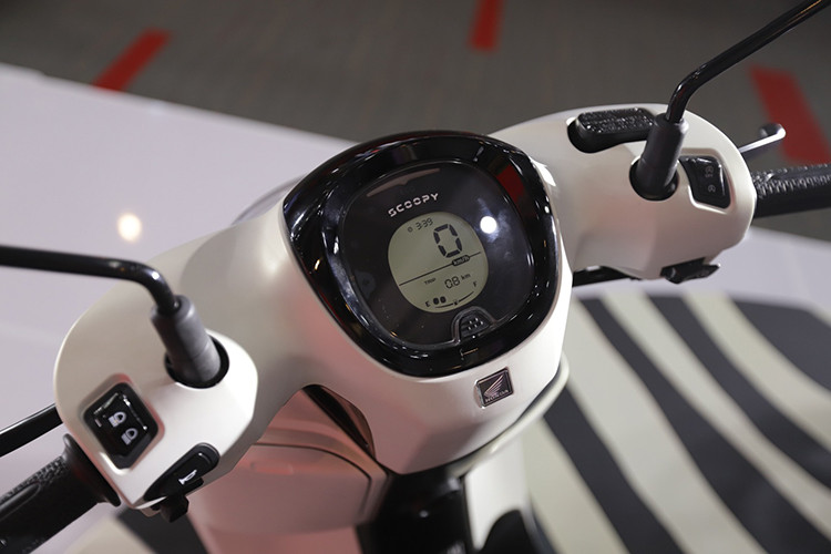 Bảng đồng hồ của Scoopy 2025 được nâng cấp lên dạng kỹ thuật số hoàn toàn với màn hình LCD hiển thị đầy đủ các thông tin quan trọng như tốc độ, mức nhiên liệu và đèn báo ECO Riding giúp tối ưu nhiên liệu. Dưới tay lái trang bị hai hộc chứa đồ, trong đó hộc bên trái có dung tích 4 lít, lớn hơn 1,3 lít so với phiên bản cũ, tích hợp cổng sạc Type-C tiện lợi.