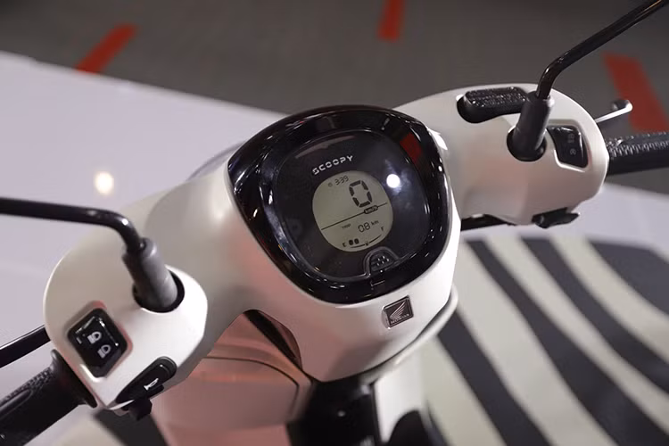 Bảng đồng hồ của Scoopy 2025 được nâng cấp lên dạng kỹ thuật số hoàn toàn với màn hình LCD hiển thị đầy đủ các thông tin quan trọng như tốc độ, mức nhiên liệu và đèn báo ECO Riding giúp tối ưu nhiên liệu. Dưới tay lái trang bị hai hộc chứa đồ, trong đó hộc bên trái có dung tích 4 lít, lớn hơn 1,3 lít so với phiên bản cũ, tích hợp cổng sạc Type-C tiện lợi.