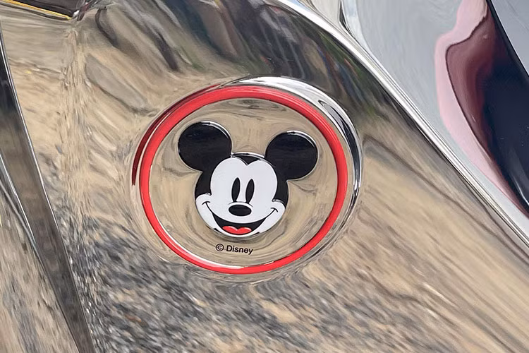 Bên cạnh đó, ở phần ốp nằm ngay cạnh cùm khoá, Honda cũng có một mảng kim loại đánh dấu phiên bản giới hạn x/100. Ở phiên bản thông thường, khu vực ốp này sẽ có phần nắp được làm bằng crom bóng, nhưng trên phiên bản Disney thì lại được làm bằng nhựa nhám.