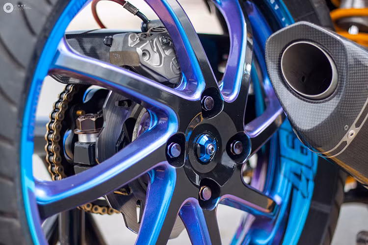 Để lắp vừa mâm Marchesini lớn ở phía sau, bộ gắp nguyên bản của Exciter 150 đã được thay bằng gắp BMW S1000RR, cùng với dè con bằng sợi carbon và bình dầu Nitron. Hệ thống phanh sau của xe cũng đã được nâng cấp triệt để với phanh Brembo Billet Nickel 2 pis đối xứng, đĩa Braking, pen đạp Brembo và bình dầu Rizoma.