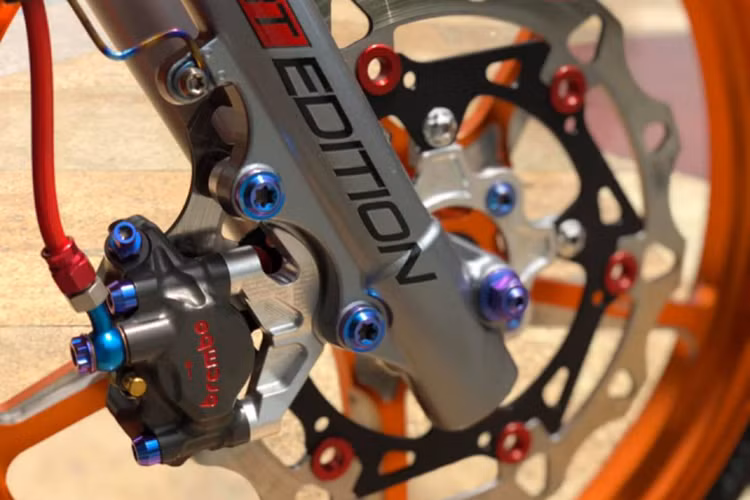 Dàn chân sử dụng heo dầu Brembo moto3 2 pis đối xứng được làm bằng chất liệu nhôm nguyên khối sau đó CNC tạo hình và phay các rãnh dầu bên trong vô cùng kì công, kèm theo đó là piston được phủ bên ngoài lớp Carbon cho khả năng chịu nhiệt cao hơn phù hợp với những chiếc xe đua phải chạy tốc độ cao liên tục.