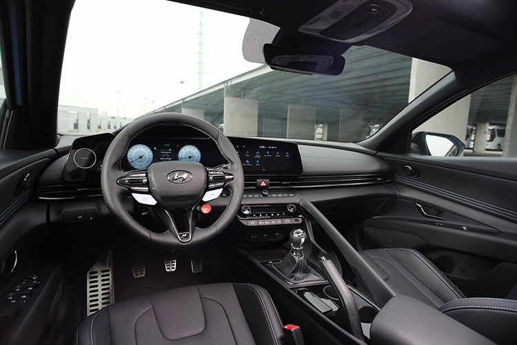 Mội thất Hyundai Elantra N mang nhiều nét đặc trưng đặc trưng của dòng xe hiệu năng cao N Brand, với logo “N” xuất hiện ở nhiều vị trí như vô-lăng, cần số, ghế ngồi, tấm ốp cửa và bàn đạp kim loại. Vô-lăng tích hợp lẫy chuyển số, phím N để chuyển đổi nhanh các chế độ tuỳ chỉnh.