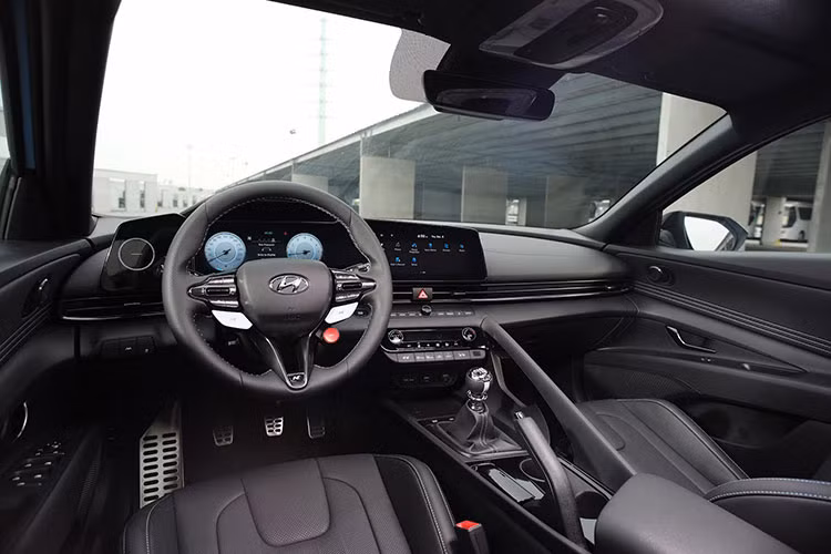 Mội thất Hyundai Elantra N mang nhiều nét đặc trưng đặc trưng của dòng xe hiệu năng cao N Brand, với logo “N” xuất hiện ở nhiều vị trí như vô-lăng, cần số, ghế ngồi, tấm ốp cửa và bàn đạp kim loại. Vô-lăng tích hợp lẫy chuyển số, phím N để chuyển đổi nhanh các chế độ tuỳ chỉnh.