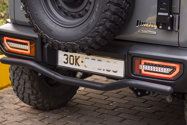 Ngoại hình chiếc Suzuki Jimny độ chất chơi đã được thay đổi mạnh mẽ với hàng loạt món đồ chơi. Điểm nhấn đầu tiên là bộ mâm sắt kết hợp lốp gai hầm hố, thay thế cho bộ lốp zin nhỏ gọn. Sự nâng cấp này không chỉ cải thiện diện mạo mà còn mang lại vẻ ngoài đậm chất xe địa hình thực thụ.