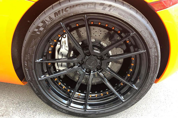 Về nguyên bản McLaren 650S Spider có bộ mâm 5 cánh kép nguyên bản màu xám khói 20 inch đẹp mắt, nhưng ở chiếc xe trong bài viết này nó đã được thay thế bằng mâm của hãng ADV.1 với thiết kế 5 chấu kép sơn đen với điểm nhấn là vành trong với những con ốc màu cam nổi bật.