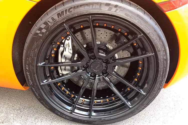 Về nguyên bản McLaren 650S Spider có bộ mâm 5 cánh kép nguyên bản màu xám khói 20 inch đẹp mắt, nhưng ở chiếc xe trong bài viết này nó đã được thay thế bằng mâm của hãng ADV.1 với thiết kế 5 chấu kép sơn đen với điểm nhấn là vành trong với những con ốc màu cam nổi bật.
