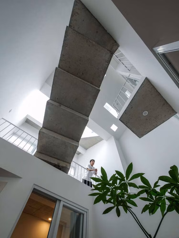Căn nhà được xây dựng trên một khu đất có phần hơi lệch ở đuôi nhà. Để khắc phục nhược điểm này, kiến trúc sư đã bố trí các không gian chức năng kết hợp giữa sân và ban công về phía sau nhà, kết nối bằng các bậc bê tông bắc qua giếng trời, tạo sự kết nối liền mạch giữa các khu vực. Ảnh: D inh R