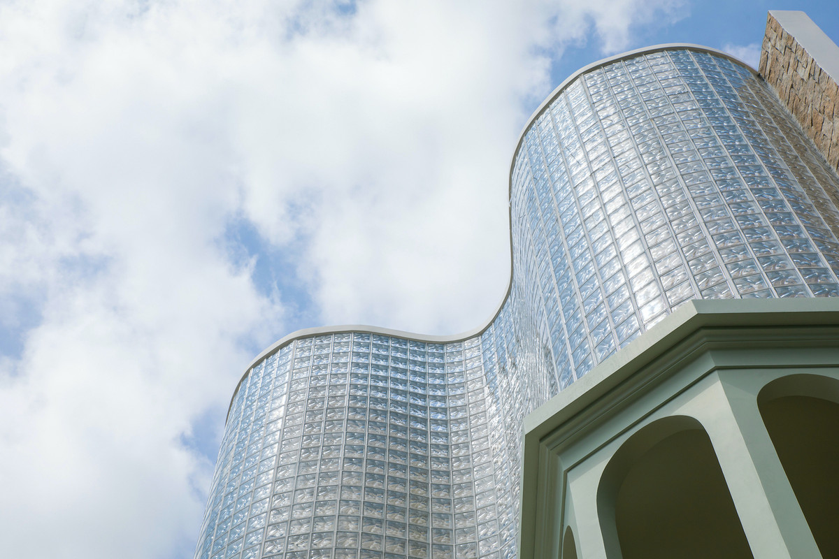 Điểm nhấn của công trình là mặt tiền cong, được xây dựng từ hơn 3.000 viên gạch kính, không chỉ tạo ấn tượng thẩm mỹ độc đáo mà còn khuếch tán ánh sáng tự nhiên vào bên trong một cách nhẹ nhàng. Ảnh: MinqBui