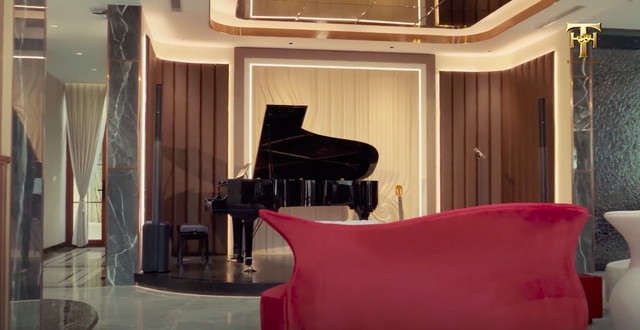 Phòng khách đặt một bộ bàn ghế to và cây đàn piano như một sân khấu mini. Ảnh chụp màn hình