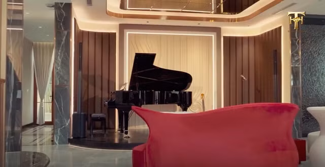 Phòng khách đặt một bộ bàn ghế to và cây đàn piano như một sân khấu mini. Ảnh chụp màn hình