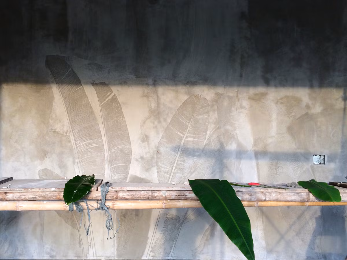 Để đem đến cảm giác thôn quê chân thực, người thợ còn sử dụng lá chuối để in vân hình lên mặt tường xi măng ướt. Ảnh: Nguyễn Tuân Nghĩa