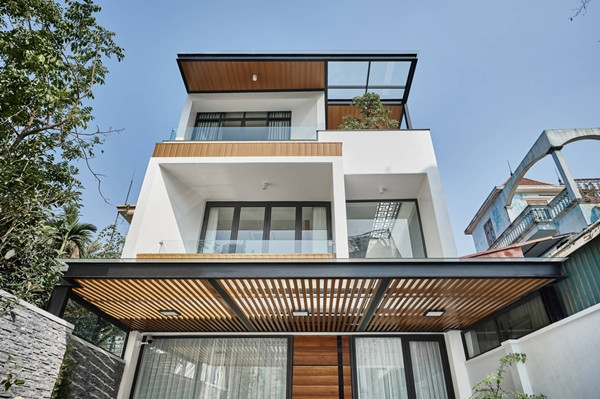 Nhà 3 tầng sở hữu vẻ ngoài “vuông thành sắc cạnh” hiện đại. Sự kết hợp khéo léo giữa các chi tiết như mái che bằng khung thép, lam nhôm, hệ nhôm giả gỗ thanh lịch ốp tường, khung cửa kính lớn...tạo điểm nhấn độc đáo cho mặt tiền. Ảnh: Wuyhoang