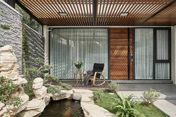 Tại phần sân trước, kiến trúc sư thiết kế khoảng hiên với bộ bàn ghế đơn đặt cạnh hồ cá Koi nhỏ. Đây là nơi gia chủ nghỉ ngơi thư giãn, uống trà. Ảnh: Wuyhoang