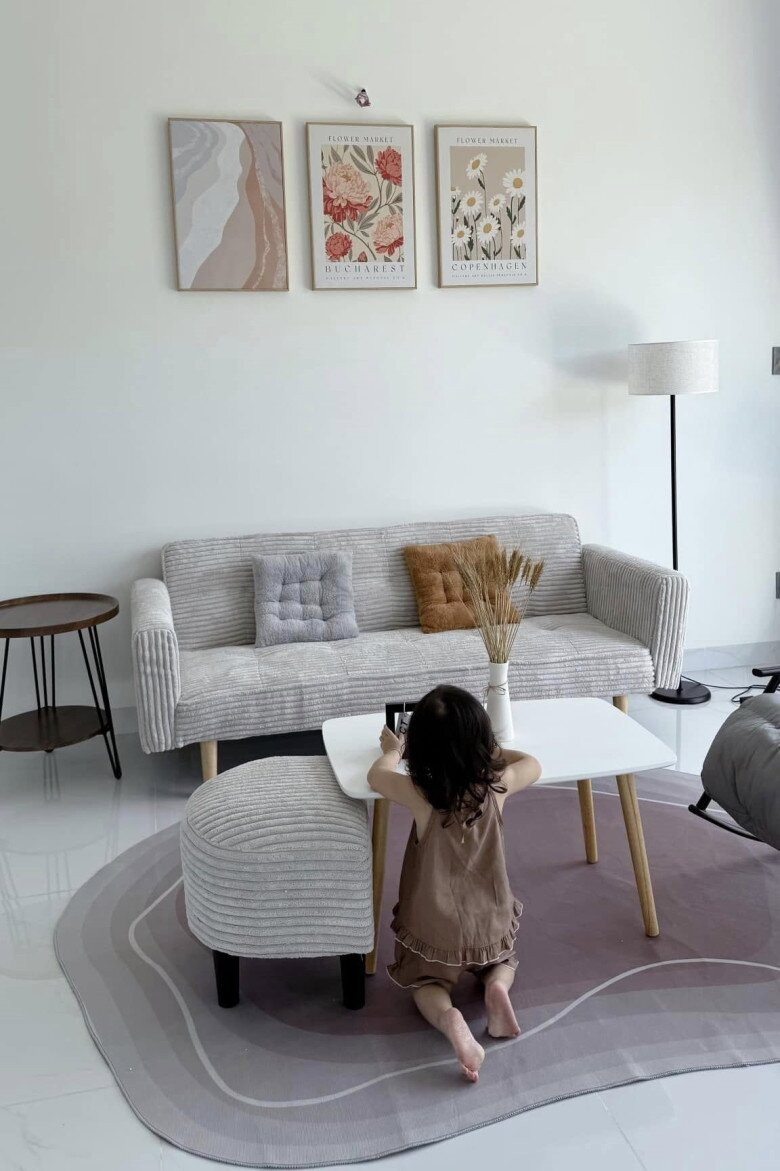 Phòng khách nổi bật với bộ sofa màu xám nhạt kết hợp bàn trà chân gỗ đơn giản. Trên tường treo những bức tranh hoa lá nhẹ nhàng tạo điểm nhấn cho căn phòng. Ảnh: FBNV