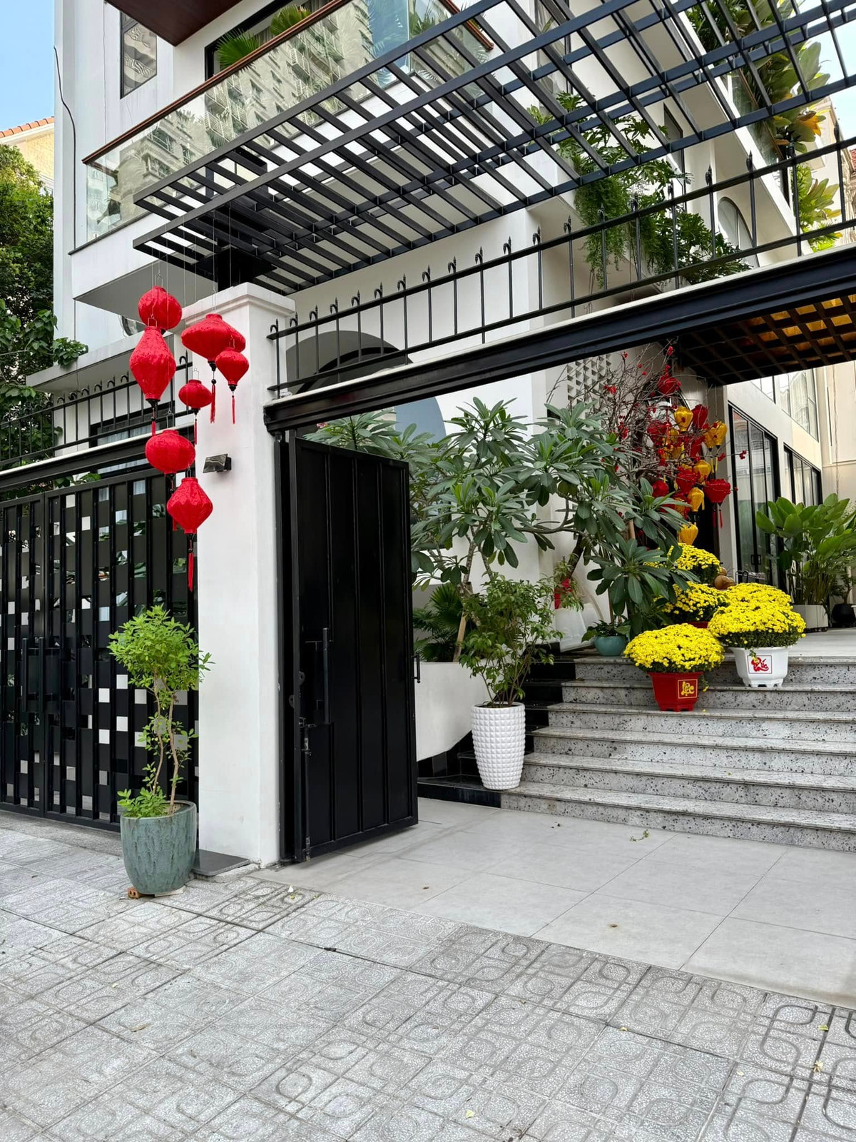 Từ ngoài cổng, biệt thự của Vân Trang phủ màu Tết với những chiếc lồng đèn đỏ và các chậu hoa cúc mâm xôi vàng rực. Ảnh: FB Vân Trang