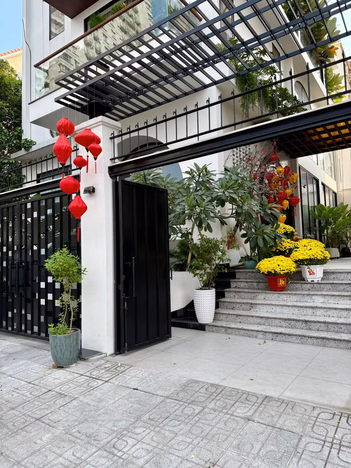 Từ ngoài cổng, biệt thự của Vân Trang phủ màu Tết với những chiếc lồng đèn đỏ và các chậu hoa cúc mâm xôi vàng rực. Ảnh: FB Vân Trang