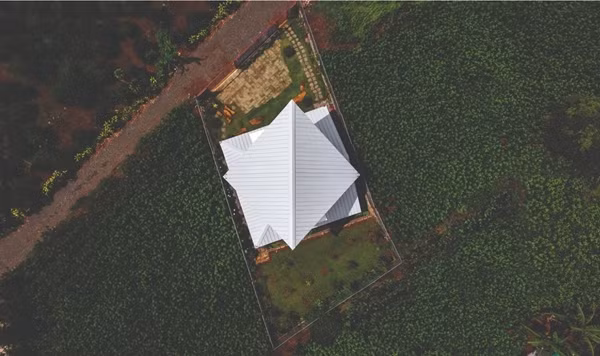 Mái gấp tole trắng không chỉ đóng vai trò chức năng mà còn trở thành điểm nhấn thị giác khi được chiếu sáng. Ảnh: Hiroyuki Oki