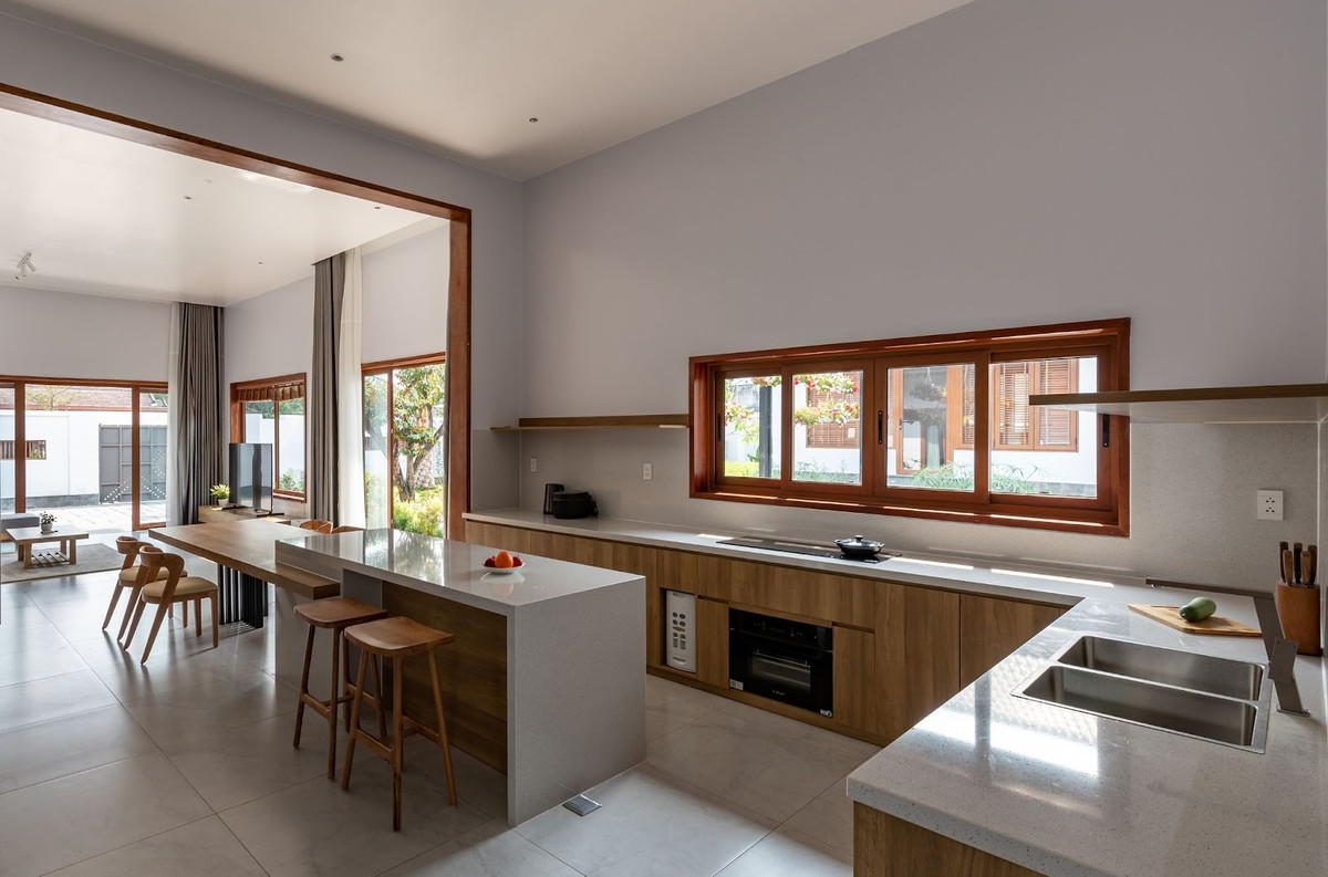 Bếp ăn nối liền mở view ra sân vườn và hồ cá Koi. Việc bố trí hồ cá Koi trước phòng khách và bếp ăn không chỉ mang đến vẻ đẹp thẩm mỹ mà còn góp phần điều hòa không khí, tạo nên một không gian sống trong lành, mát mẻ. Đây là một giải pháp thông minh, đặc biệt phù hợp với khí hậu nóng ẩm của Tây Ninh. Ảnh: Story Architecture