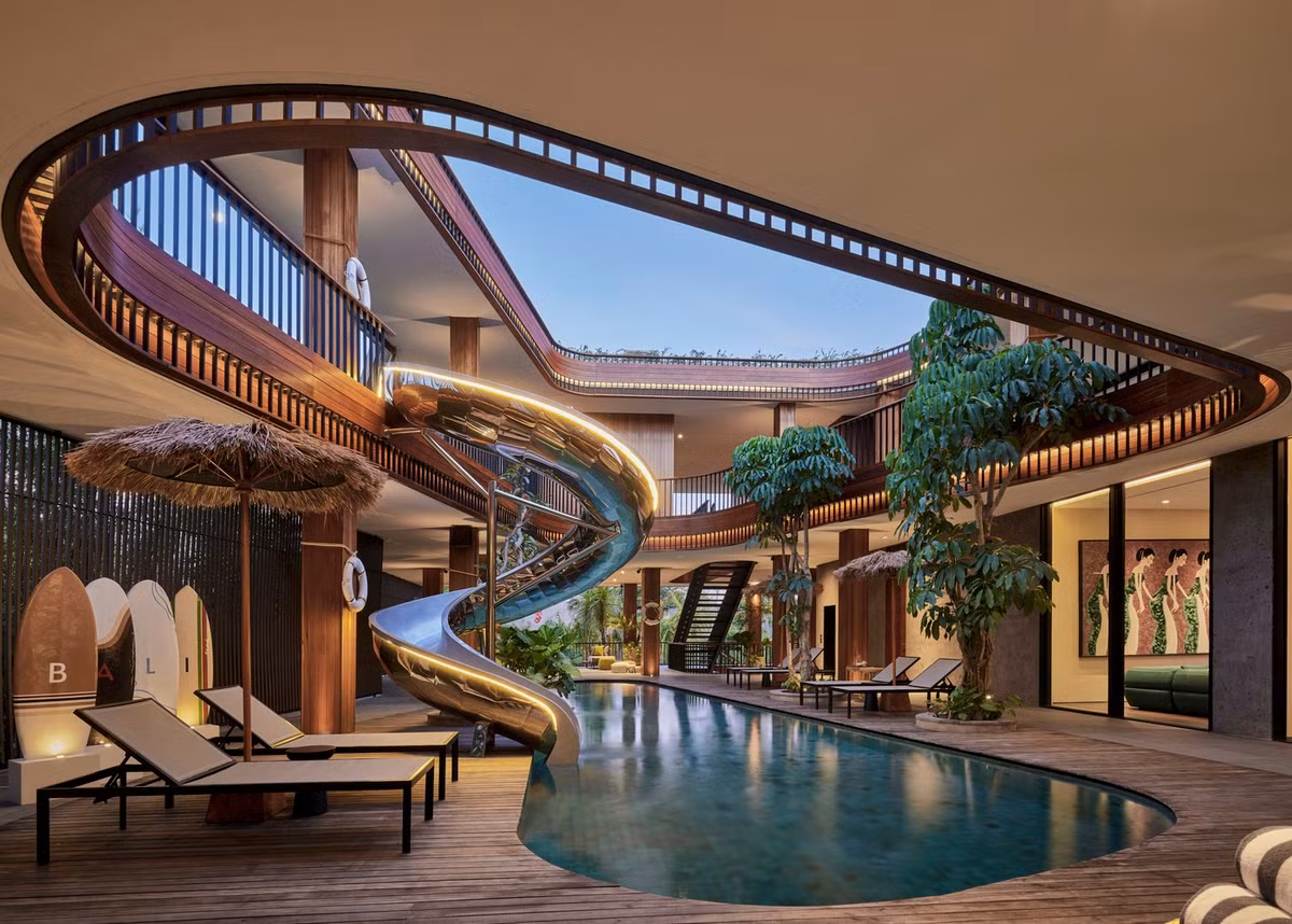 Tâm điểm của ngôi nhà là khoảng giếng trời lớn ở khu vực trung tâm cùng một đường trượt nước lớn, uốn cong như cơn lốc xoáy. Ảnh: KIE