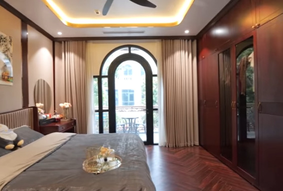 Biệt thự 4 tầng có 3 phòng ngủ. Phòng ngủ master trên tầng 2 được ốp sàn gỗ xương cá, tạo cảm giác rộng hơn. Ảnh chụp màn hình NhaF