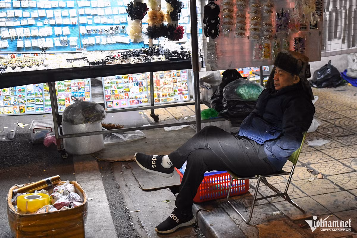 Tại chợ đêm Đồng Xuân, một người bán hàng co ro ngồi chờ khách. 0h30, nhiều tiểu thương của các sạp hàng quanh đó đã rục rịch dọn đồ ra về sớm hơn thường lệ.