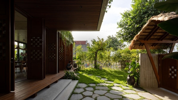 Hàng rào kết hợp giữa gỗ tự nhiên và bụi trúc, mang đến một cảm giác mộc mạc, gợi nhớ về không gian làng quê Việt. Ảnh: SuKha_Studio