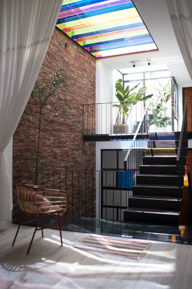 Các ô cửa kính và chùm thuỷ tinh ở giếng trời tạo ra hiện tượng phản quang thú vị như những chùm cầu vồng lấp lánh trong không gian nhà. Ảnh: Han Deo