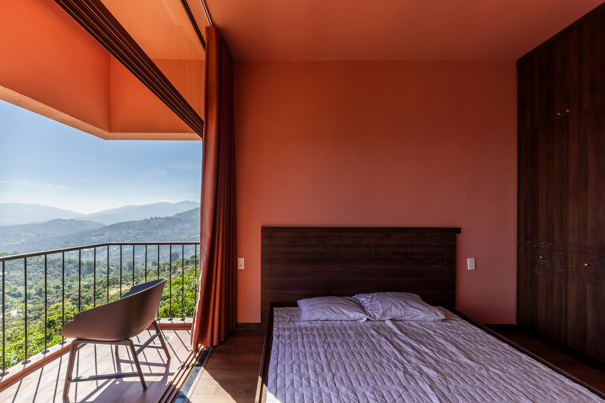 Phòng ngủ được bố trí ở vị trí cao hơn, nổi bật với gam màu hồng dịu dàng kết hợp cùng sắc trầm ấm của gỗ. Ảnh: Hiroyuki Oki