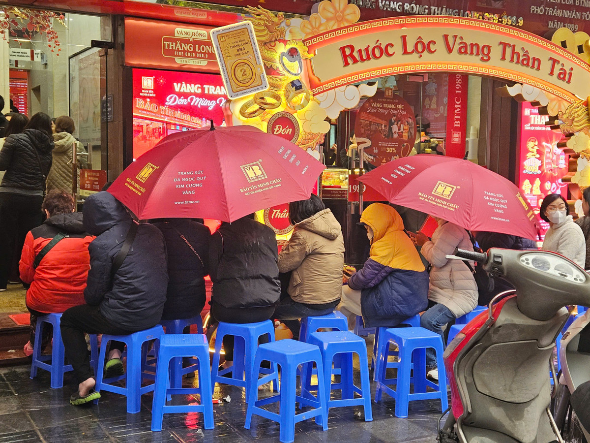 Dù trời mưa phùn, nhiều người vẫn kiên nhẫn che ô đợi đến lượt để mua vàng.