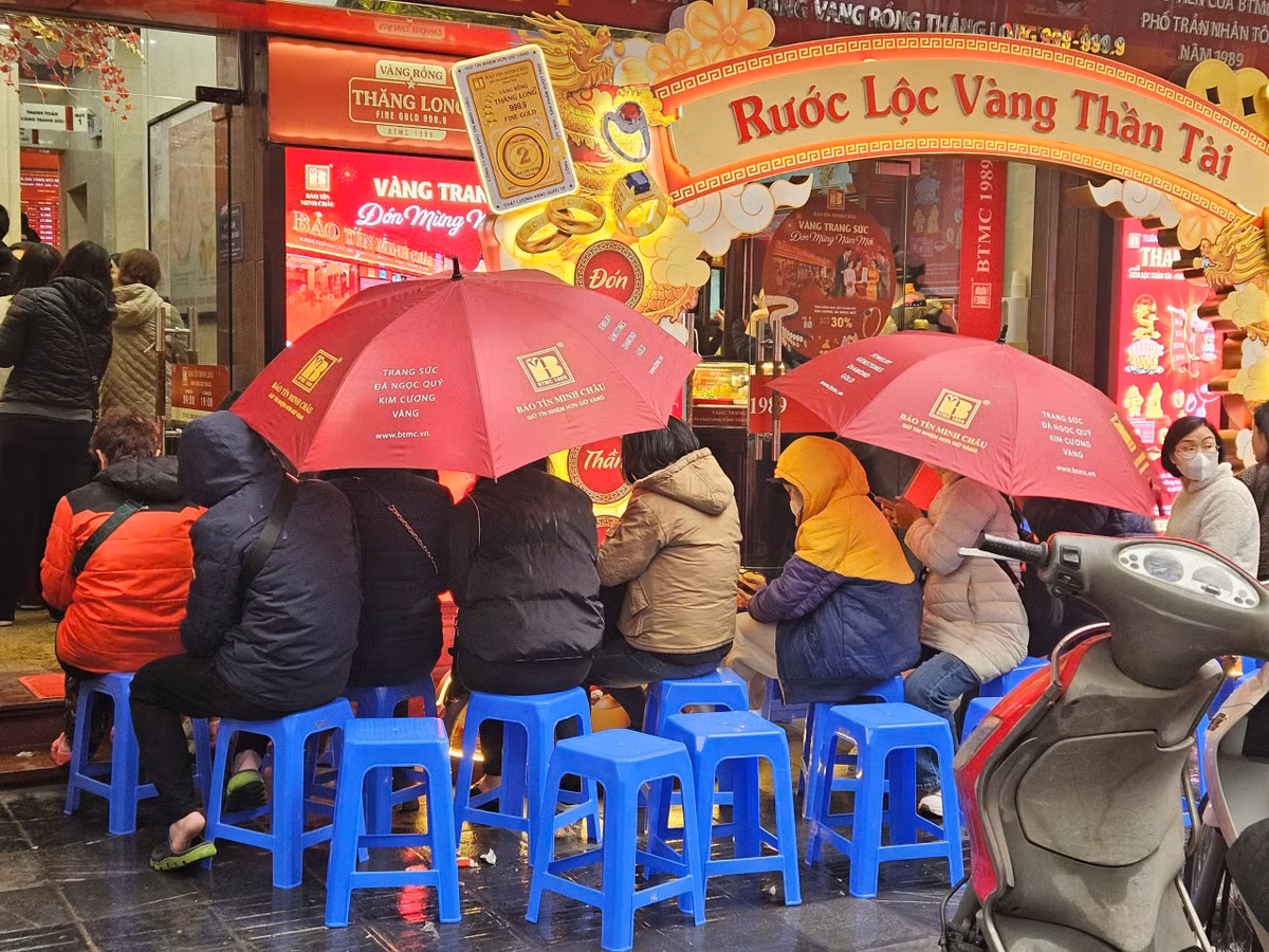 Dù trời mưa phùn, nhiều người vẫn kiên nhẫn che ô đợi đến lượt để mua vàng.