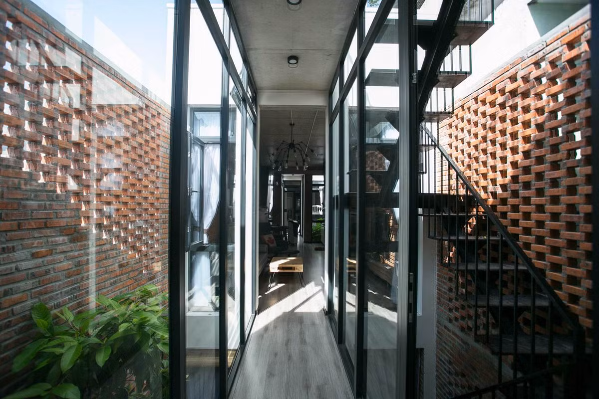 Ngoài ra, do ngôi nhà hẹp nên kiến trúc sư sử dụng nhiều tường kính và cửa kính để lấy ánh sáng và gió vào nhà nhiều hơn. Ảnh: 85 Thiết kế