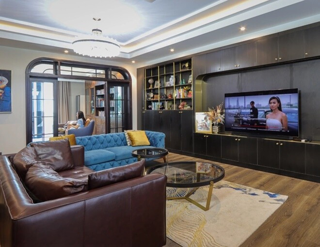 Phòng khách rộng rãi với hai bộ sofa xanh, nâu và bàn trà kính tròn. Ảnh: FBNV