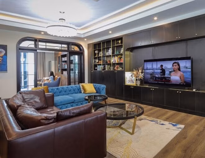 Phòng khách rộng rãi với hai bộ sofa xanh, nâu và bàn trà kính tròn. Ảnh: FBNV