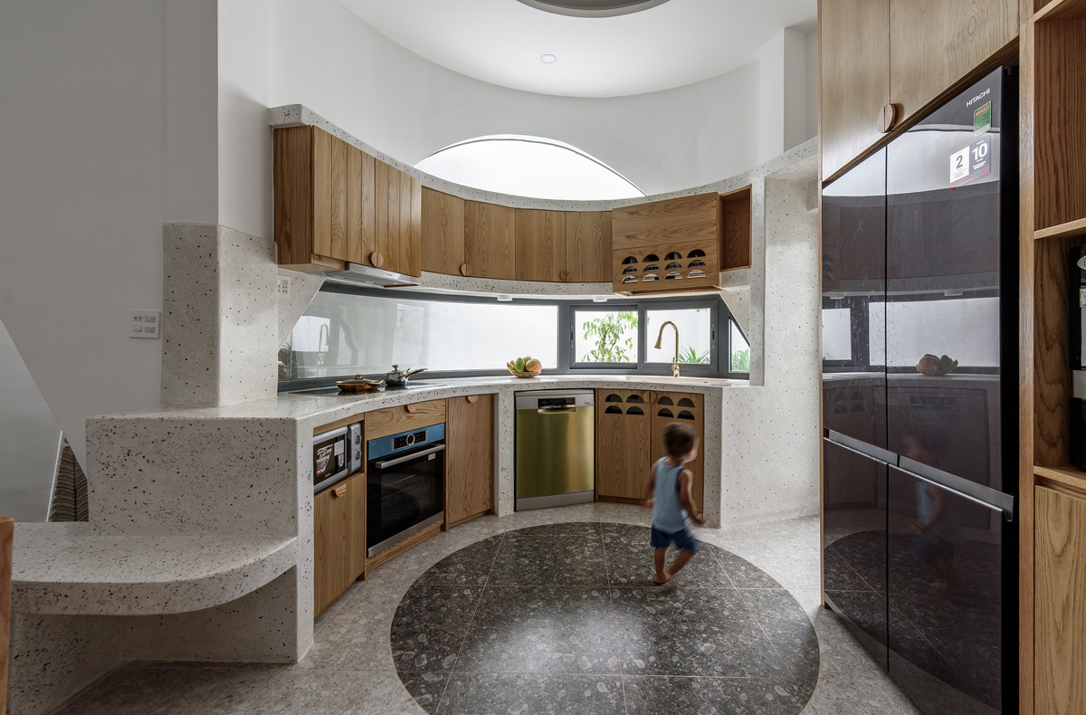 Bếp thiết kế như một đường cong mềm mại, có cửa sổ lấy ánh sáng. Ảnh: Lonton Studio