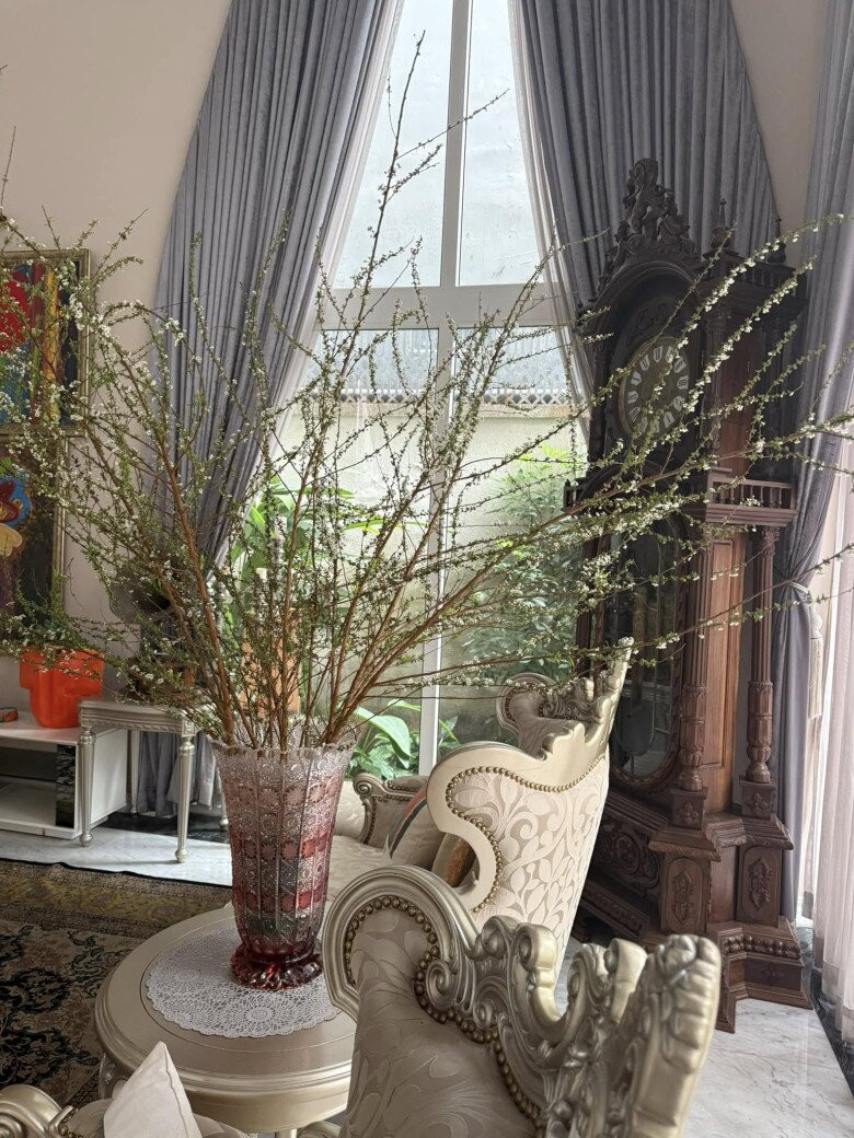 Một góc phòng khách được tô điểm bởi bình hoa trắng và đồng hồ gỗ chạm khắc cầu kỳ. Ảnh: FBNV