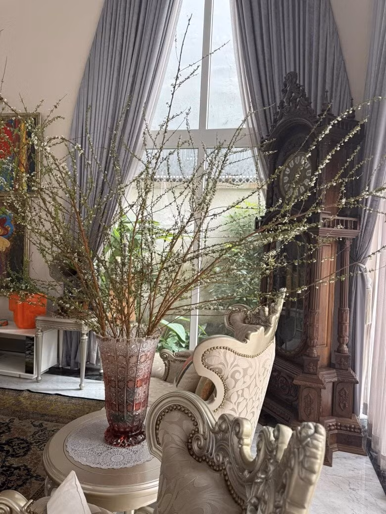 Một góc phòng khách được tô điểm bởi bình hoa trắng và đồng hồ gỗ chạm khắc cầu kỳ. Ảnh: FBNV