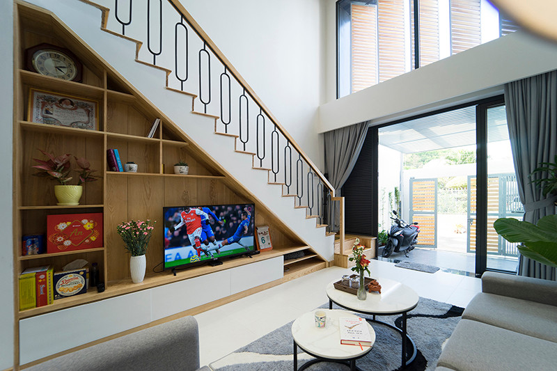 Phòng khách thiết kế kệ âm tường cầu thang giúp tối ưu diện tích. Ảnh: QPS House