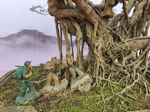 Dưới gốc cây, chủ nhân có trang trí hình ảnh các chú bộ đội đang hành quân với balo và khẩu súng vác trên vai. Ảnh: Người đưa tin